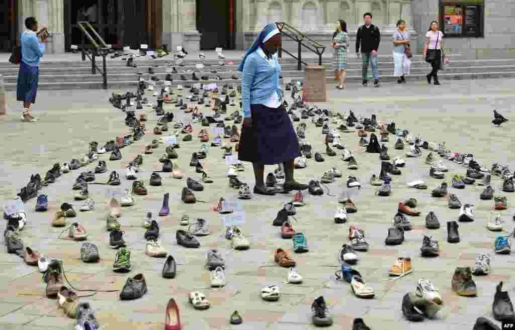 Catholic Agency For Overseas Development&#39;s (CAFOD) Sister Clara from Zambia walks through shoes displayed outside Westminster Cathedral in central London to promote Pope Francis&#39; refugee campaign. The campaign is calling for world leaders to back global agreements aimed at assisting refugees and migrants.