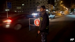 FILE - A Palestinian Hamas police officer monitors the road as a checkpoint is set up at night in Gaza City, May 5, 2015.