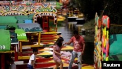 Personas bajan de una trajinera, un bote en Xochimilco en Ciudad de México. El gobierno mexicano instó a la población a mantener una "distancia saludable" paracevitar la infección con la enfermedad COVID-19, producida por un nuevo coronavirus.