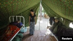 Injured people are treated outside a damaged hospital in Thabeik Kyin township, Burma, November 12, 2012. 