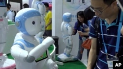 In this image taken from video, visitors look at iPal robots during the Shanghai CES electronic show in Shanghai, China, June 8, 2017. More than 50 companies are showcasing a new generation of robots at this week's Shanghai CES electronics show, most of which serve as companions at home, or butlers in shopping malls.