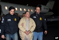 In this photo provided U.S. law enforcement, authorities escort Joaquin "El Chapo" Guzman, center, from a plane to a waiting caravan of SUVs at Long Island MacArthur Airport, Jan. 19, 2017, in Ronkonkoma, N.Y.