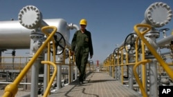 FILE - An oil technician makes his way to the oil separator facilities in Iran's Azadegan oil field southwest of Tehran, April 15, 2008.