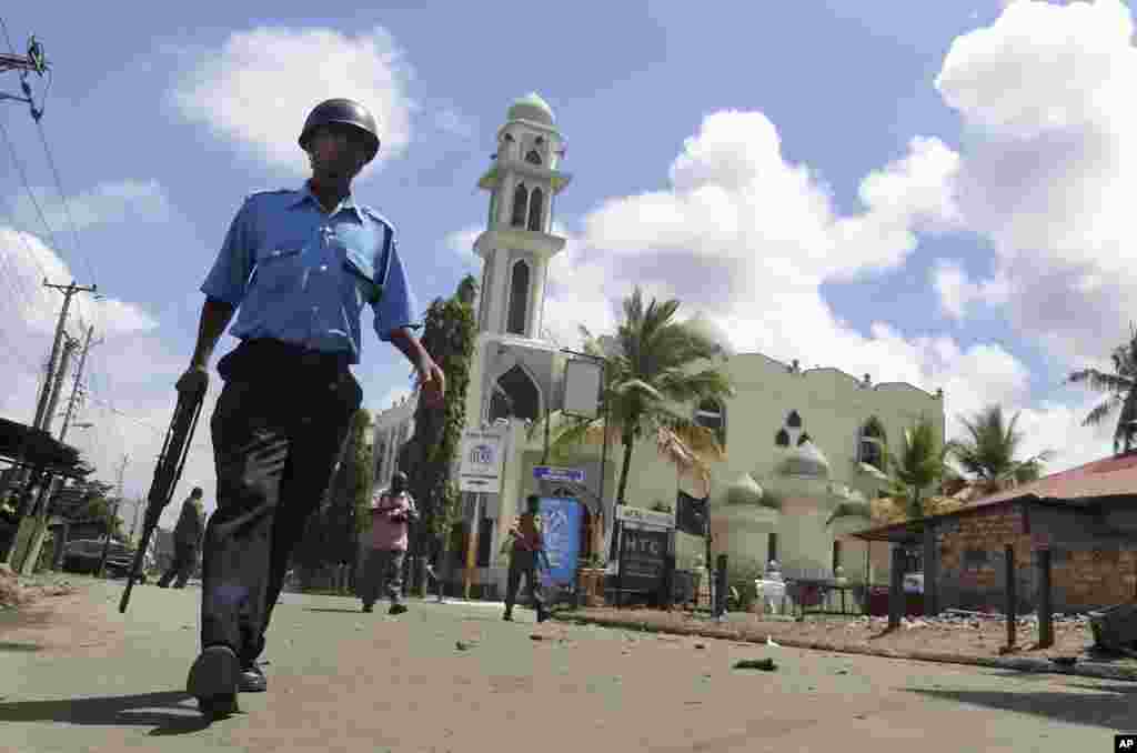 An armed Kenyan police officer patrols near the Masjid Musa Mosque, where Muslim cleric Sheikh Ibrahim Ismael who was killed Thusday night preached, following rioting after Friday prayers, Mombasa, Kenya, Oct. 4, 2013.
