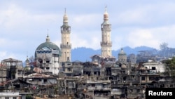 FILE - A sign that reads "I love Marawi" is seen in front of damaged houses, buildings and a mosque inside a war-torn Marawi city, southern Philippines, Oct. 26, 2017.