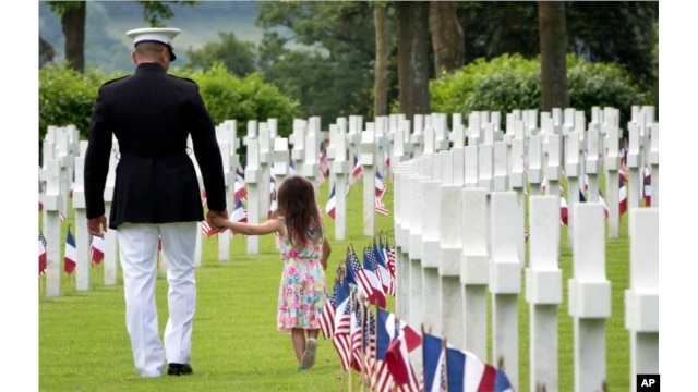 Les sentiments entre soldats peuvent devenir très proches. Ici, un soldat du corps des Marines américains tient la main d'une petite fille alors qu'ils marchent parmi les pierres tombales des morts de la Première Guerre mondiale au cimetière américain d'Aisne-Marne à Belleau, en France, en mai 2018.