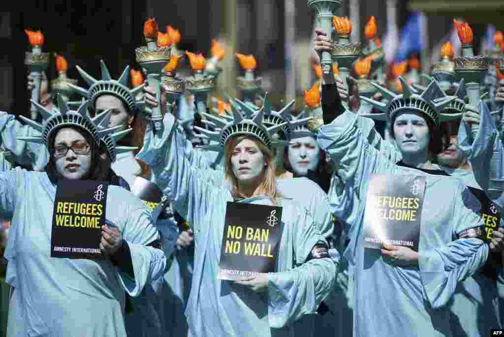 Para aktivis dari organisasi Amnesty International berpakaian seperti patung Liberty melakukan protes atas kebijakan pengungsi Presiden AS Donald Trump di luar Kedutaan Besar AS di London.