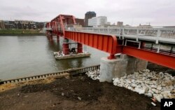In this March 28, 2017, photo, the Red Bridge pedestrian bridge is seen over the Des Moines River in Des Moines, Iowa. A little more than a decade after it was restored, crews went back to the site with a crane to hoist the span more than 4 feet higher.