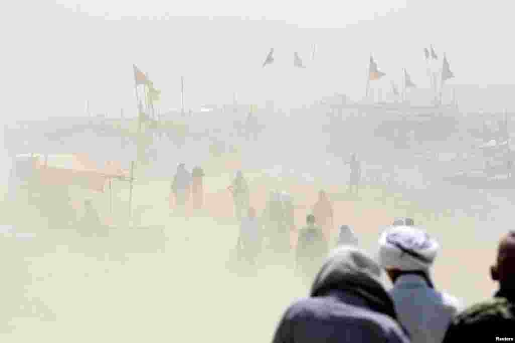 People walk through a dust storm on the banks of the Ganga river in Allahabad, India.