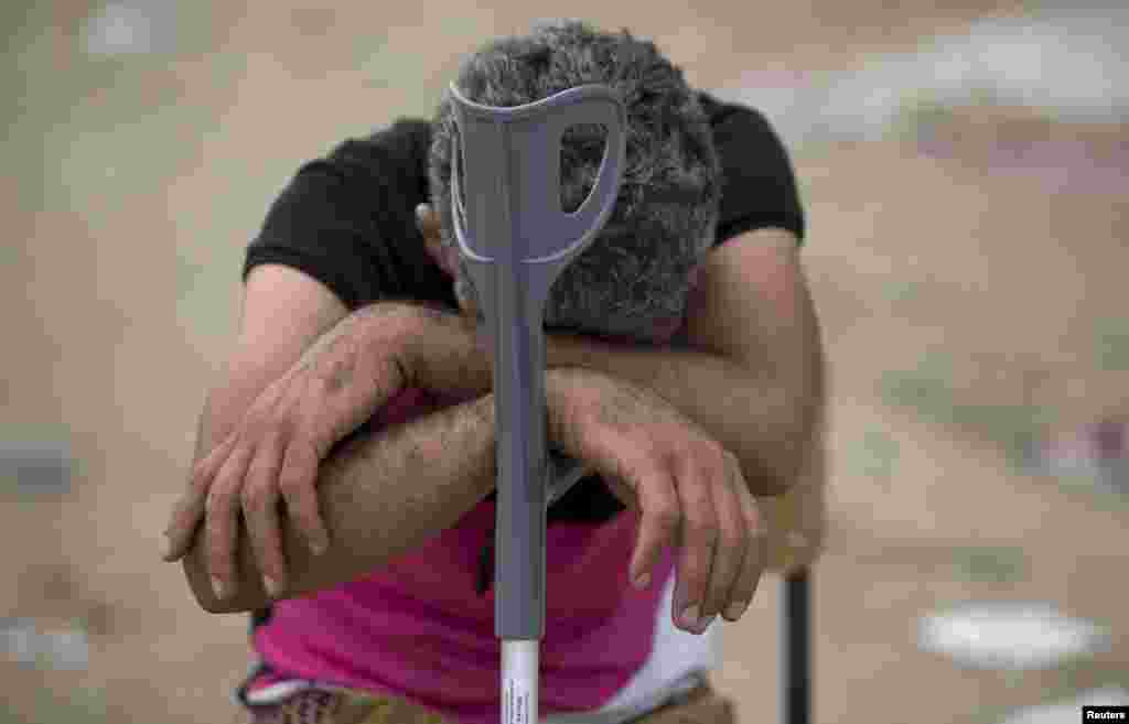 A migrant rests on a crutch as he waits to enter a camp for registration procedure after crossing the Macedonian-Greek border near Gevgelija, Macedonia, Sept. 6, 2015.