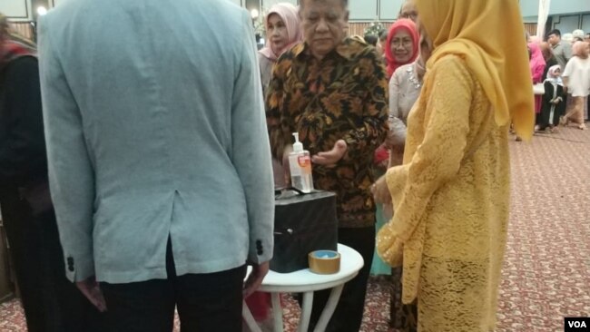 Tamu undangan menggunakan penyanitasi tangan yang disediakan pengantin
