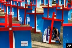 Carlos Felice, a 37-year-old Venezuelan living in Panama for five years, right, confesses to local Catholic priest Gabriel Agustin Guardia in an outdoor confessional, after exercising with his dog at Omar Park in Panama City, Jan. 23, 2019. Pope Francis arrived in the country later in the day.