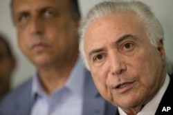 Brazil's President Michel Temer, right, talks to the press next to the Governor of Rio de Janeiro Luiz Fernando Pezao after a meeting with local authorities about the implementation of a decree that has placed the military in charge of Rio's state security at the Guanabara Palace in Rio de Janeiro, Feb. 17, 2018.