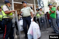 A police officer carries his shopping out of a department store, which was forced by the government to cut prices by at least 50 percent on all merchandise after an inspection, in Caracas Nov. 15, 2013.