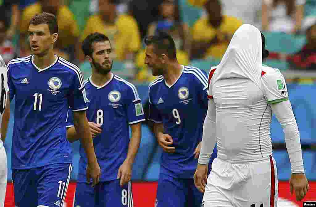 Iranian Andranik Teymourian covers his face as Bosnians Edin Dzeko, Miralem Pjanic and Vedad Ibisevic celebrate their team&#39;s second goal at the Fonte Nova arena, in Salvador, June 25, 2014. 