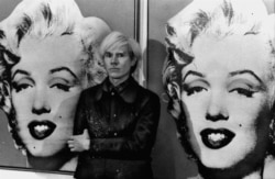 America's pop art painter and filmmaker, Andy Warhol, stands in front of his double portrait of the late Hollywood film star, Marilyn Monroe, at The Tate Gallery in London, February 15, 1971, at a press preview of his exhibition. (AP Photo)