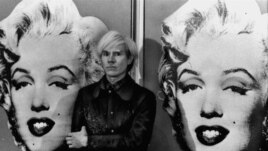 America's pop art painter and filmmaker, Andy Warhol, stands in front of his double portrait of the late Hollywood film star, Marilyn Monroe, at The Tate Gallery in London, February 15, 1971, at a press preview of his exhibition. (AP Photo)