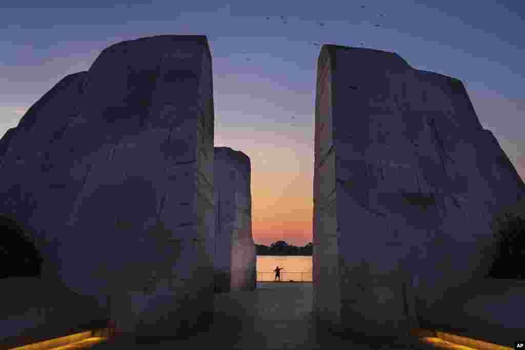 Framed in the Martin Luther King, Jr. Memorial a fisherman casts his line into the Tidal Basin at dawn in Washington.