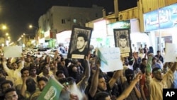 Saudi Shi'ite protesters hold Saudi flags and portraits of unidentified prisoners during a demonstration in Qatif, Saudi Arabia, March 9, 2011