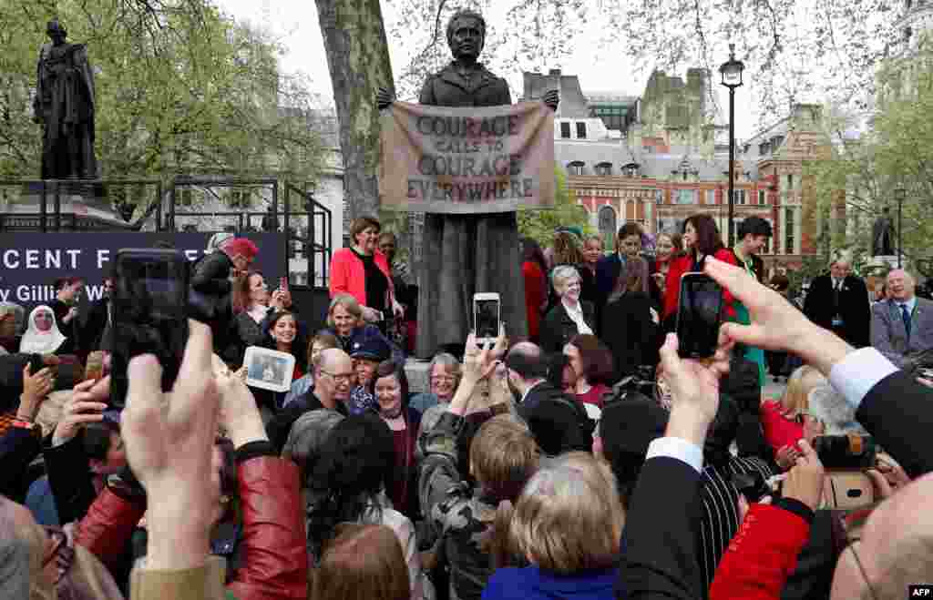 People pose for photographs with a statue of suffragist and women&#39;s rights campaigner Millicent Fawcett by British artist Gillian Wearing after it was unveiled in Parliament Square in London.