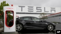 FILE - A Tesla car is parked at a charging station outside the Tesla factory in Fremont, California, May 14, 2015.