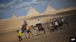Tourists ride camels near the pyramids, in Giza, Egypt, January 31, 2011. The pyramids are closed to tourists.