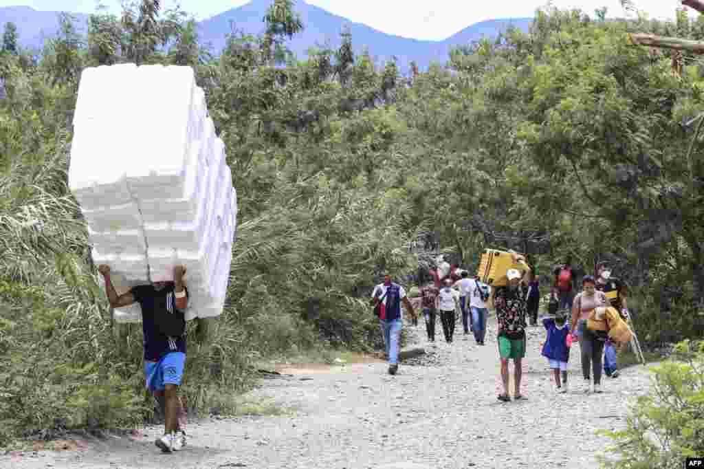 People cross from San Antonio del Tachira in Venezuela to Cucuta in Colombia through "trochas" - illegal trails- near the Simon Bolivar International Bridge, Oct. 5, 2021.