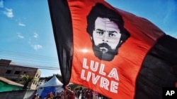 Un partidario del ex presidente brasileño, Luiz Inácio Lula da Silva, alza una pancarta decorada con una imagen que representa a da Silva, frente al Departamento de Policía Federal, donde está cumpliendo condena en la cárcel.