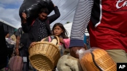 Brittany Rios, of Honduras, center, carries stuffed animals in a wicker basket as her family leaves a shelter for members of the Central American migrant caravan in Tijuana, Mexico, Nov. 30, 2018. 
