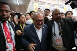 Papua New Guinea Prime Minister Peter O'Neill is escorted by security as he is pursued by reporters after reading his statement at the end of the APEC 2018 summit at Port Moresby, Papua New Guinea, Nov. 18, 2018.