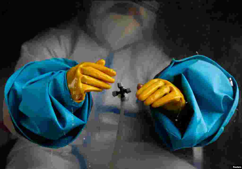 A health worker wearing personal protective equipment sanitizes his gloves before taking a polymerase chain reaction test from a mobile swab collection vehicle, amid the second wave of the coronavirus disease, in Kathmandu, Nepal.