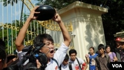 Một sinh viên biểu tình trước cổng Đại học Yangon cầm một cái bát úp, biểu tượng của sự chống đối ở Myanmar, Yangon, Myanmar, ngày 15 tháng 11, 2014. (Steve Herman/VOA )