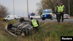 A Surete du Quebec officer investigates an overturned vehicle in Saint-Jean-sur-Richelieu, Quebec, Oct. 20, 2014. Two Canadian soldiers were injured, and one died, in a hit-and-run Monday by a male driver who later was shot by police officers.