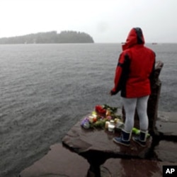 A woman stands on the shore in front of Utoeya island, northwest of Oslo, July 24, 2011