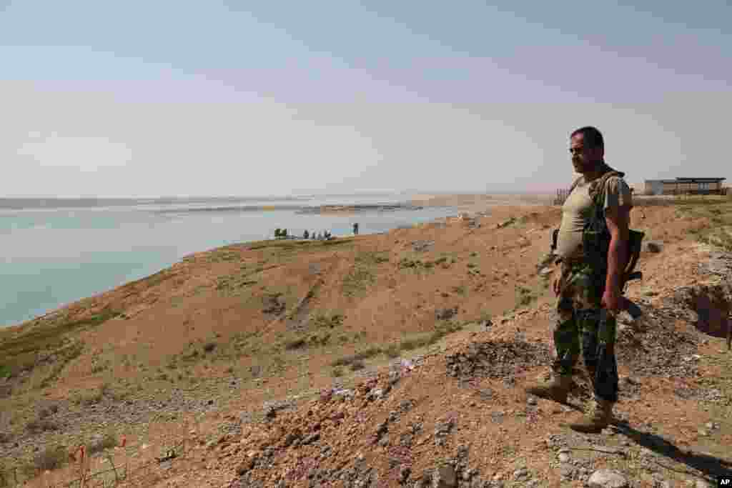 A Kurdish peshmerga fighter stands guard at the Mosul Dam, near the town of Chamibarakat, outside Mosul, Iraq, Aug. 17, 2014.