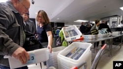 In this photo taken April 6, 2017, passengers reach for bins as they prepare to go through a security checkpoint at Washington's Seattle-Tacoma International Airport.