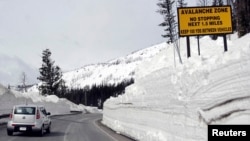 FILE - A car travels the newly plowed east entrance road over Sylvan Pass in Yellowstone National Park shortly after the park opened in this photo taken in May 2011.
