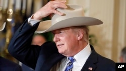 Presiden Donald Trump mencoba topi Stetson dalam pameran produksi dalam negeri “Made in Amerika” di di Gedung Putih, Washington, 17 Juli 2017. Pameran tersebut menampilkan produk-produk khas yang dibuat di setiap 50 negara bagian AS.
