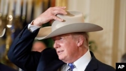 Presiden Donald Trump mencoba topi Stetson saat pameran "Made in America," yang menampilkan produk yang menampilkan barang-barang yang dibuat di masing-masing 50 negara Bagian AS di Gedung Putih pada 17 Juli 2017.