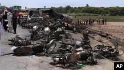 Pakistan army soldiers stands guard while rescue workers examine the site of an oil tanker explosion at a highway near Bahawalpur, Pakistan, June 25, 2017.