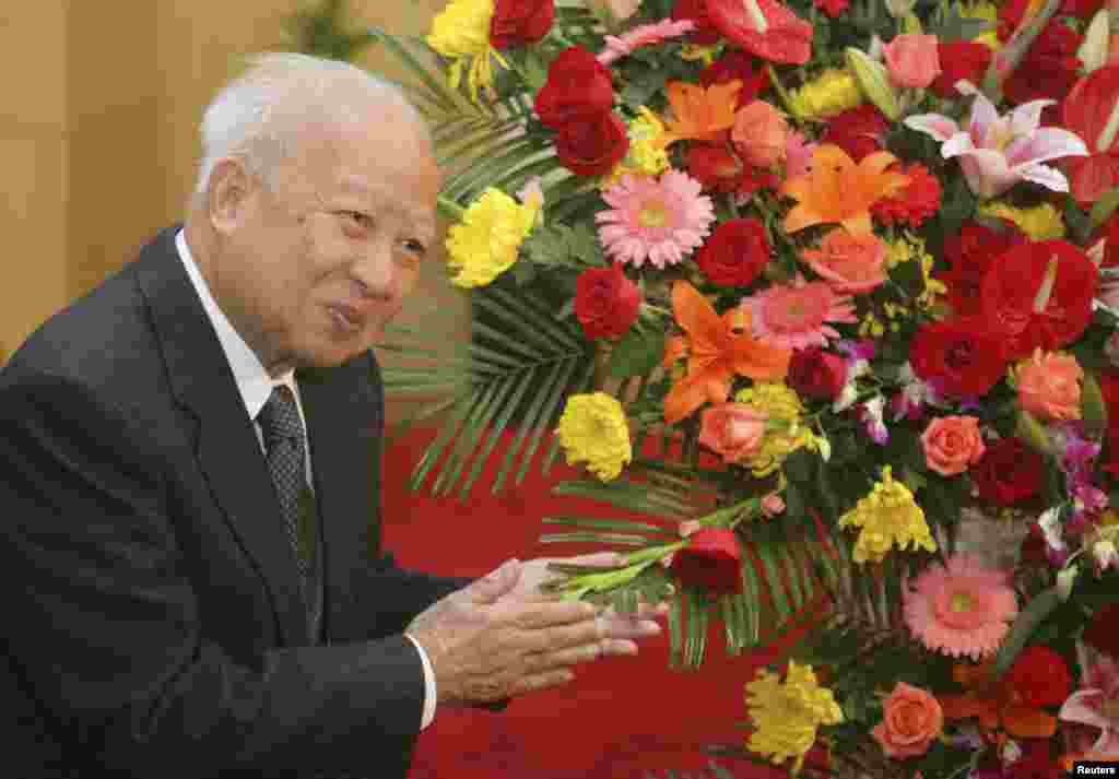 Then Cambodian King Norodom Sihanouk stands beside flowers given by the Chinese government during a meeting with Chinese State Councilor Dai Bingguo (not seen) in Beijing, October 30, 2006.