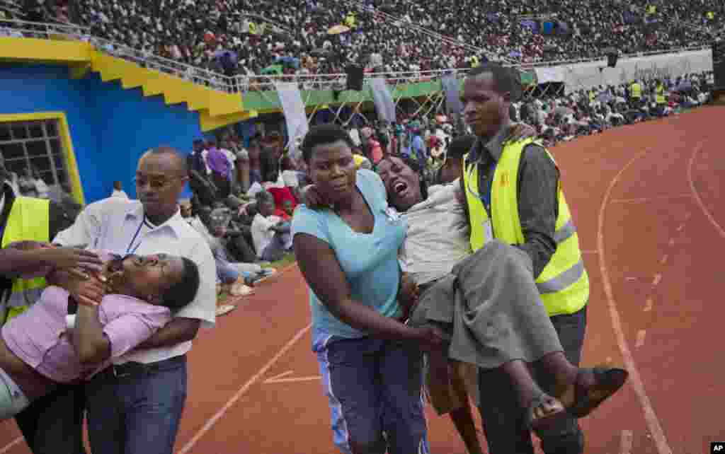 Two wailing women, some of dozens overcome by grief at recalling the horror of the genocide, are carried away to receive help during a ceremony to mark the 20th anniversary of the Rwandan genocide, at Amahoro stadium in Kigali, April 7, 2014.