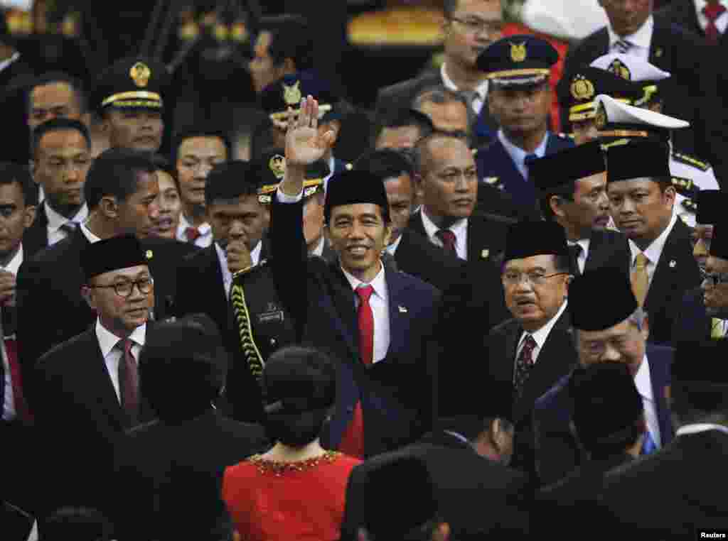 Presiden baru Joko Widodo meambaikan tangannya usai diambil sumpahnya di Gedung DPR di Jakarta (20/10), didampingi Wakil Presiden Jusuf Kalla. (Reuters/Darren Whiteside)