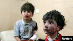 Injured children cry after, according to activists, two barrel bombs were thrown by forces loyal to Syria's president Bashar Al-Assad in Hullok neighbourhood of Aleppo, May 1, 2014. 
