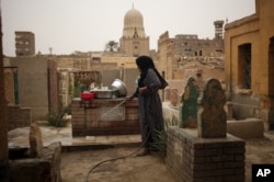 A woman who lives in the Cairo Necropolis cleans a tomb, outside her home in Cairo, Egypt, October 23, 2015. In the sprawling Cairo Necropolis, known as the City of the Dead, life and death are side by side.