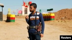 FILE - An officer of the Syrian Kurdish Democratic Union Party (PYD) stands guard near the Syrian-Iraq border. 