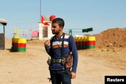 FILE - An officer of the Syrian Kurdish Democratic Union Party (PYD) stands guard near the Syrian-Iraq border.