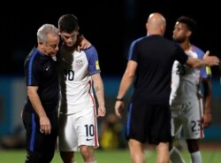 FILE -- In this Oct. 10, 2017, photo, U.S. player Christian Pulisic, (10) is comforted by assistant coach Dave Sarachan after losing 2-1 against Trinidad and Tobago during a 2018 World Cup qualifying soccer match in Couva, Trinidad.