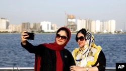 FILE - Iranians take a selfie at the Persian Gulf Martyrs lake, west of Tehran, July 7, 2019. Some daring women in Iran's capital have been taking off their mandatory headscarves, or hijabs, in public, risking arrest.