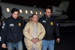 FILE - In this photo provided U.S. law enforcement, authorities escort Joaquin "El Chapo" Guzman, center, from a plane to a waiting caravan of SUVs at Long Island MacArthur Airport, Jan. 19, 2017, in Ronkonkoma, N.Y.